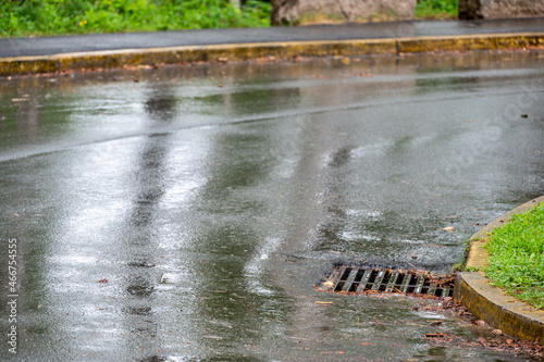 Metal storm drain during a rain event with leaves and needles starting to buildup around the edges © Lost_in_the_Midwest