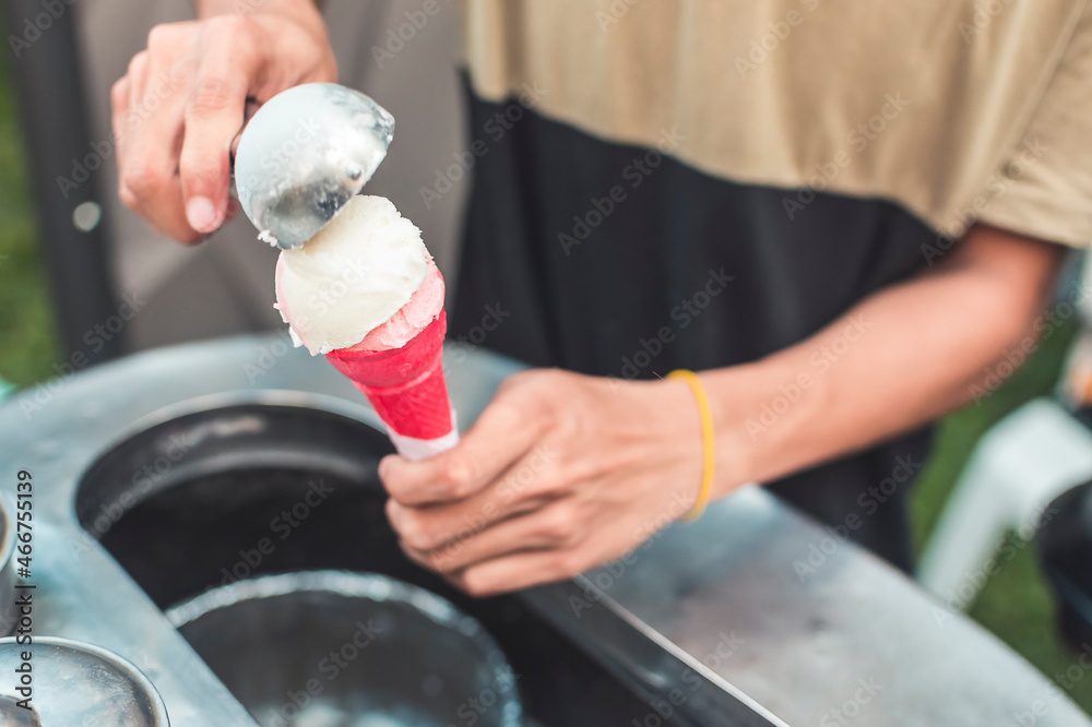 An ice cream vendor places scoops of coconut and strawberry sorbetes