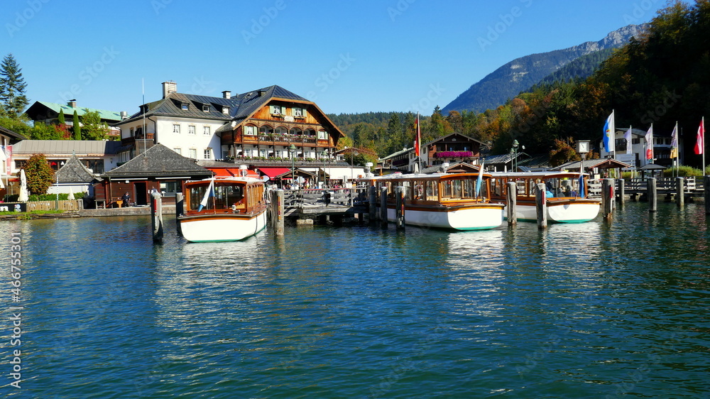malerischer Hafen in Schönau am Königssee mit Wald, Hotel und Booten auf blauem Wasser in der Sonne