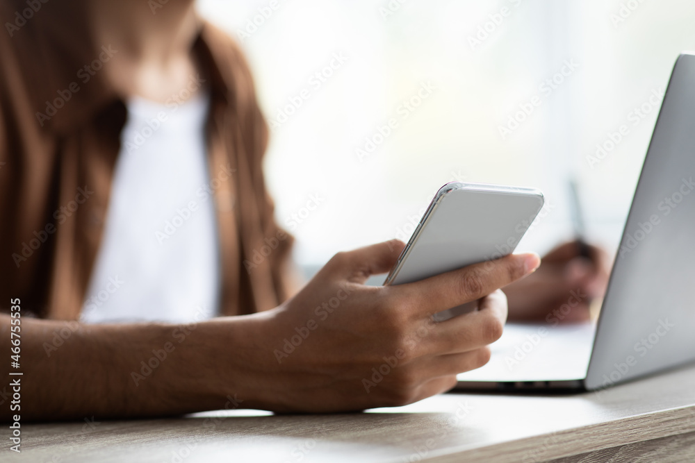 Cropped of man using cellphone while working on laptop Cropped of man using cellphone while working on laptop