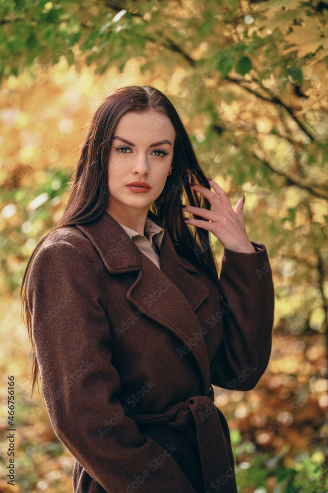 Young beautiful woman in brown coat in the park in autumn Young beautiful woman in brown coat in the park in autumn