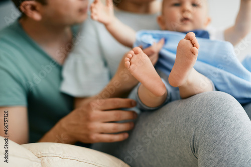 Close-up of baby and his parents enjoy in time together at home. Focus is on baby's feet.