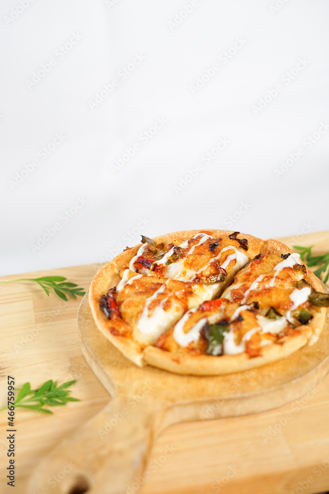 four slices of pizza on the wooden paddle or peel. a tasty Italian baked food with spicy topping on it. it's served on the wooden table with some leaves decorate it.