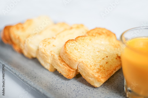 a close up look of some toasted bread served on a plate with a cup of orange juice. a perfect menu for western breakfast.