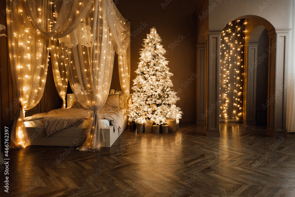 magic warm and cozy evening in Christmas brown white room interior design, Xmas tree decorated lights garland holiday living room.canopy bed arch sofa mirror style New year holidays magic warm and cozy evening in Christmas brown white room interior design, Xmas tree decorated lights garland holiday living room.canopy bed arch sofa mirror style New year holidays