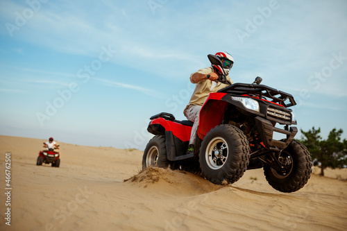 Two men in helmets ride on atv, action view