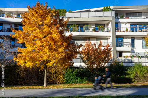 Urbanes Wohnen in München: Neubaugebiet am Hirschgarten im Herbst mit Bewohnern: Mann mit Kinderwagen photo