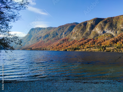 Bohinj lake in Triglav national park, Slovenia. Autumn landscape in the dusk, scenic view of the water, mountains and colorful trees 