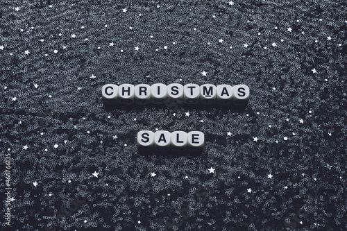 Christmas sale words on new year black night fabric tulle, background with silver glitter star. Christmas sale dark backdrop with shine star sequin