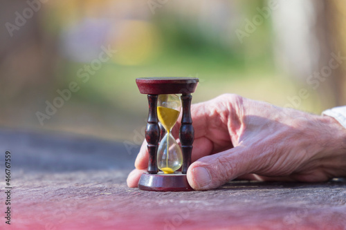 Hourglass in the hands of an old man who understands that life is short