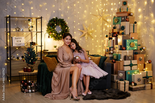 Christmas and new year concept - beautiful mother with her cute daughter sitting in decorated room with heap of christmas gifts © Di Studio