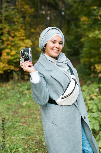 Young Arab Woman wearing hijab headscarf photographing with a smartphone in park. Modern muslim girl © satura_