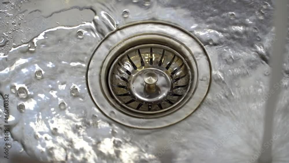 water streaming in sink. water stream going down the drain. water streaming in sink. water stream going down the drain.
