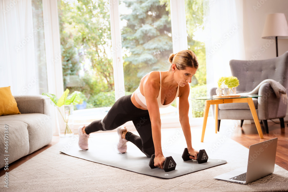 Shot of sporty woman using a dumbbells while exercising at home Shot of sporty woman using a dumbbells while exercising at home