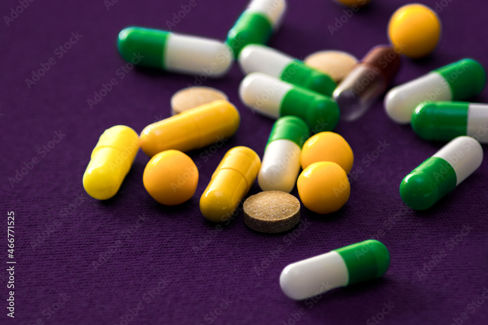 Medical pills. Color capsules medication. Purple background. Health care concept. Free space for text. Medicines. Many different pills. Chemical industry.
