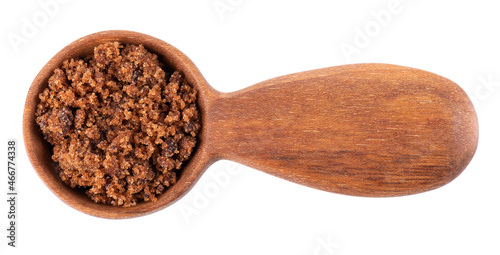 Muscovado sugar in wooden spoon, isolated on white background. Barbados sugar, khandsari or khand. Top view. photo