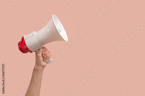 Megaphone in woman hands on a pink background.