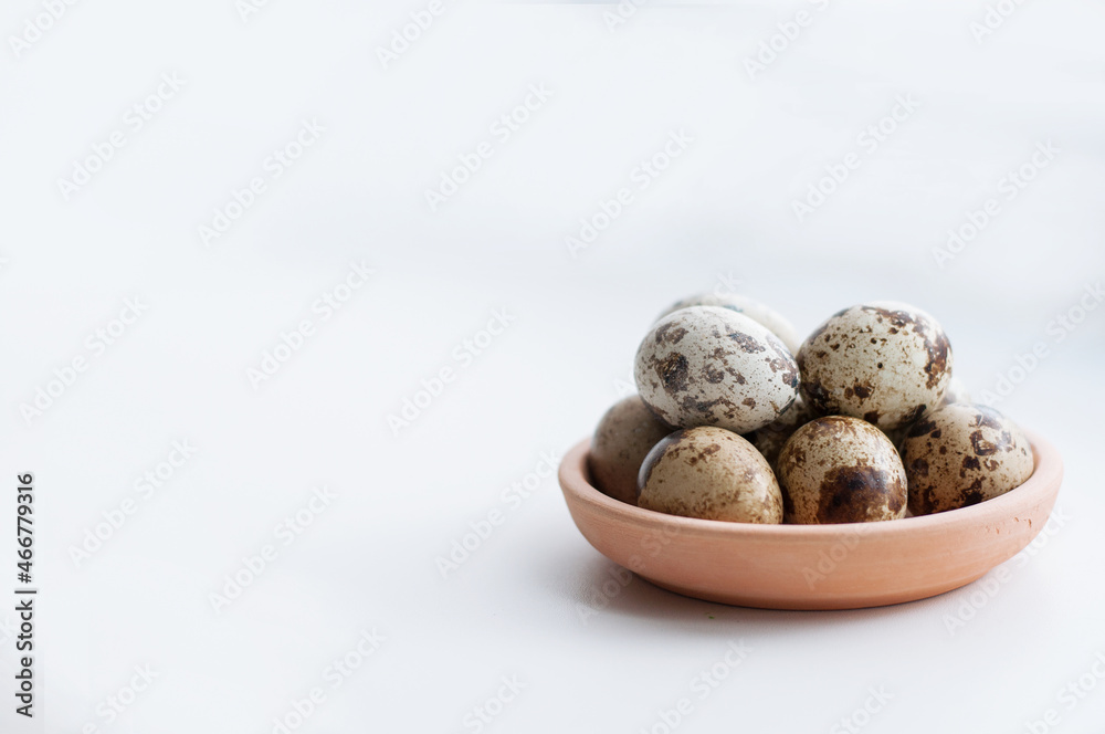 Quail eggs in a clay saucer on a white background Quail eggs in a clay saucer on a white background