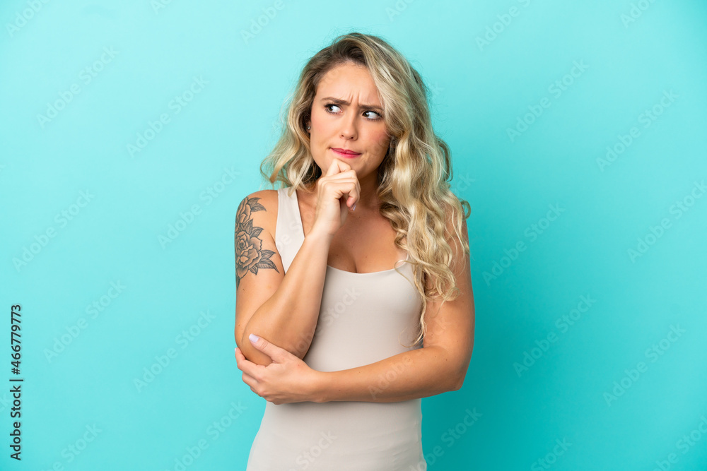 Young Brazilian woman isolated on blue background having doubts and thinking Young Brazilian woman isolated on blue background having doubts and thinking