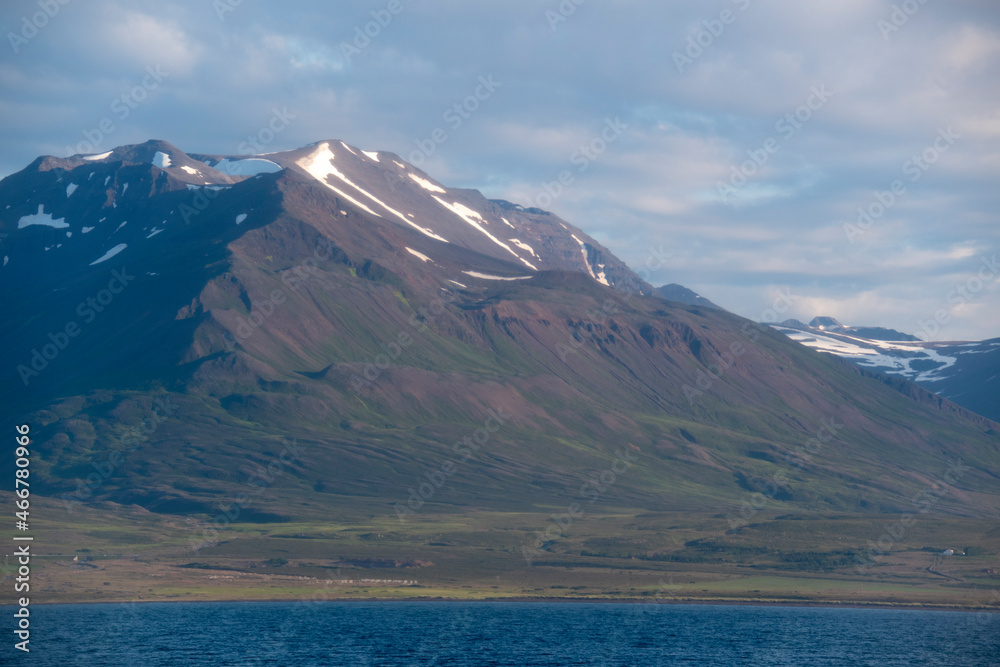 Landscape of snow covered mountains from ferry in fjord in North Iceland