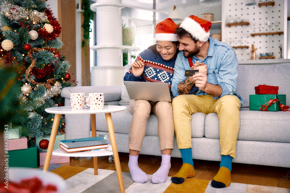 Fototapeta premium Young couple shopping online with credit card at home for Christmas