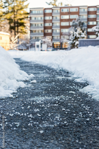 Winter road with salt for melting snow and apartment building