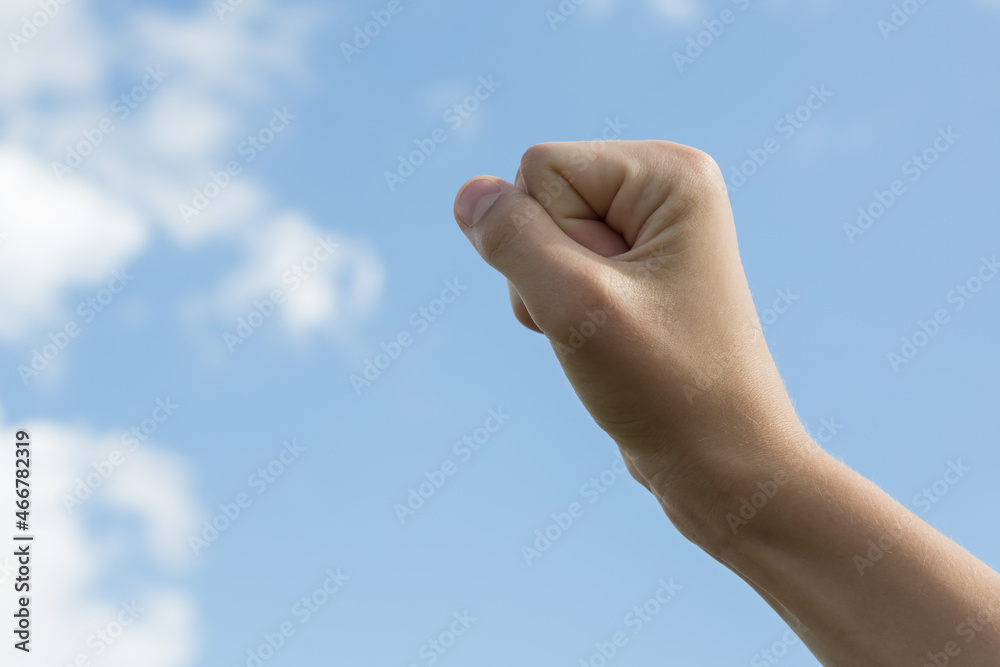 A hand in a fist against a blue sky. Concept A hand in a fist against a blue sky. Concept