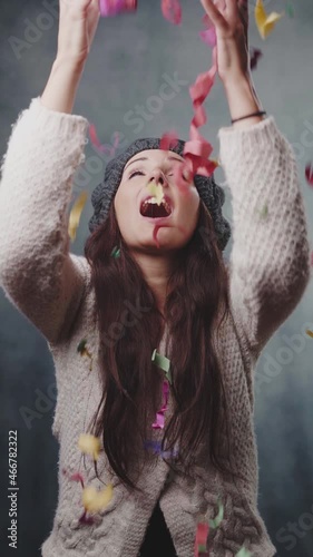 Beautiful 20s woman holding present joyfully celebrating, sharing Christmas or birthday gifts boxes, giving and taking concept, confetti falling on long hair model smile. Vertical slow-motion footage