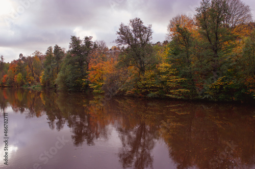 River lined with colorful trees in autumn  reflecting in the water in Sweden.