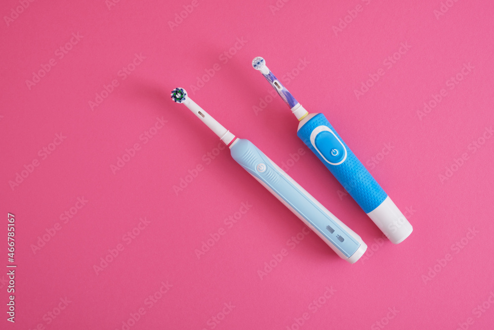 two electric blue toothbrushes on bright pink background oral hygiene concept two electric blue toothbrushes on bright pink background oral hygiene concept