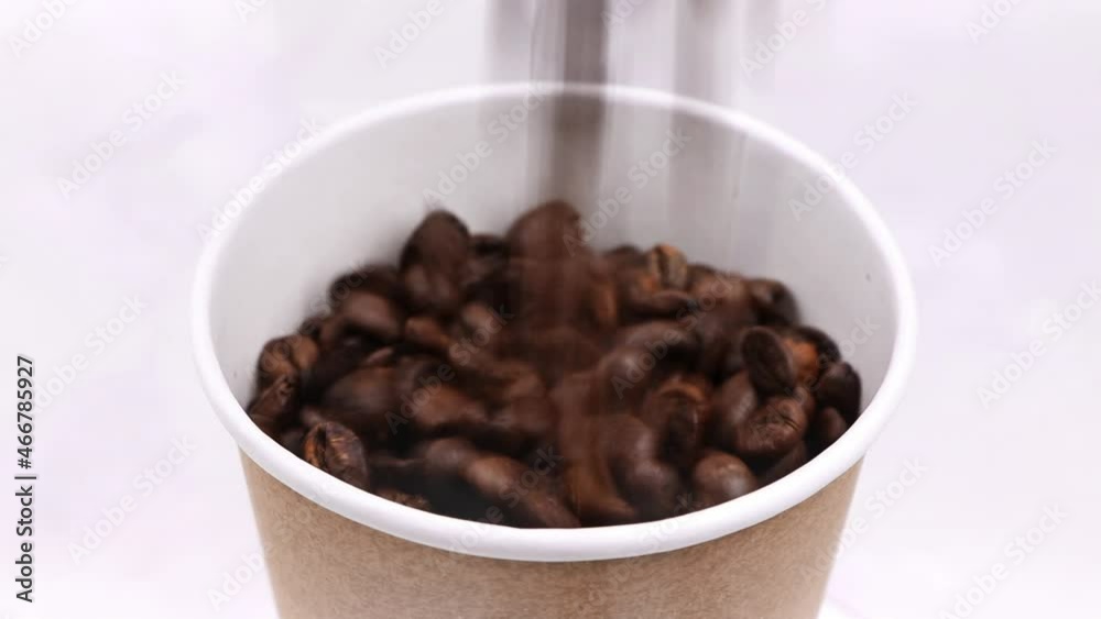 Rotating roasted coffee beans in paper cup. Roasted coffee beans. White background. Rotating roasted coffee beans in paper cup. Roasted coffee beans. White background.