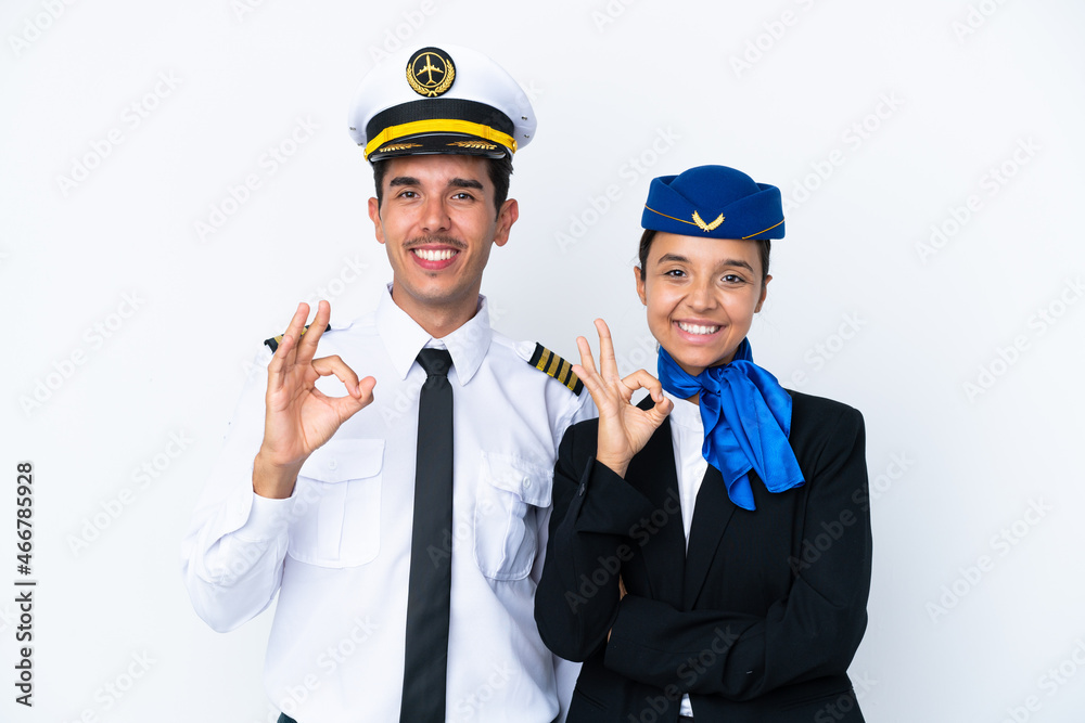 Airplane pilot and mixed race air hostess isolated on white background showing an ok sign with fingers Airplane pilot and mixed race air hostess isolated on white background showing an ok sign with fingers