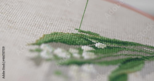 A man is embroidering with a cross on the canvas with green floss threads. Close-up. photo