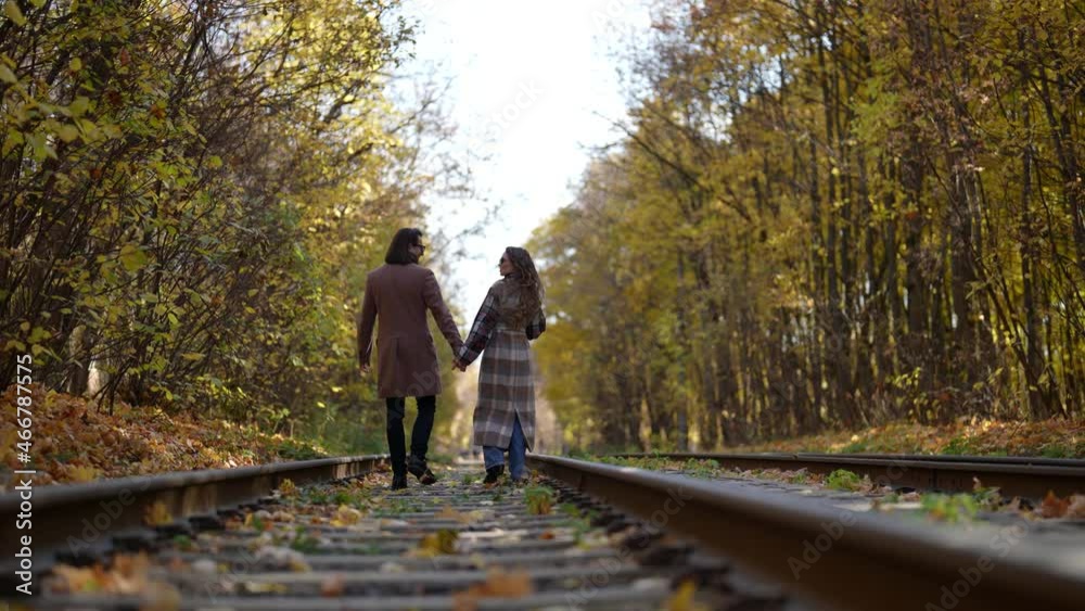 romantic walk of loving couple in autumn day, strolling on old railway road