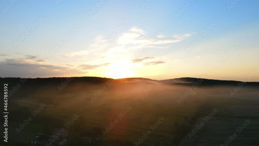 A magical sunset over the village, where the fog descends. Sunset from aerial view. A haze of fog in the sun. A balloon is on the horizon A magical sunset over the village, where the fog descends. Sunset from aerial view. A haze of fog in the sun. A balloon is on the horizon
