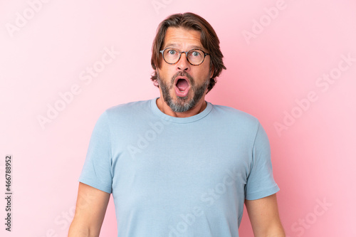 Senior dutch man isolated on pink background With glasses and surprised expression © luismolinero