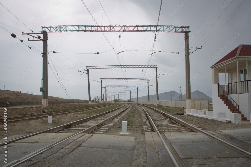 Railway tracks turn to the left. Rails for the train, laid on a hill above the city, smoothly turn left. Technological background. Blue sky over the railr . The local railway station on the rural area