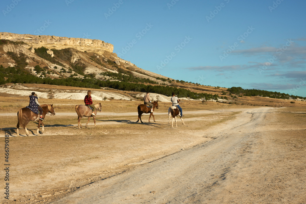  A group of tourists travels on horseback through the rocky terrain. Copy space.