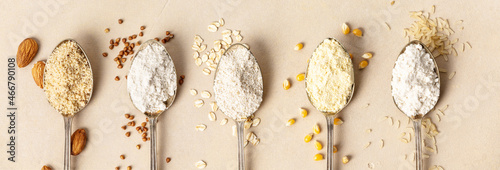 Metal spoons of various gluten free flour almond flour, oatmeal flour, buckwheat flour, rice flour, corn flour , flat lay, top view