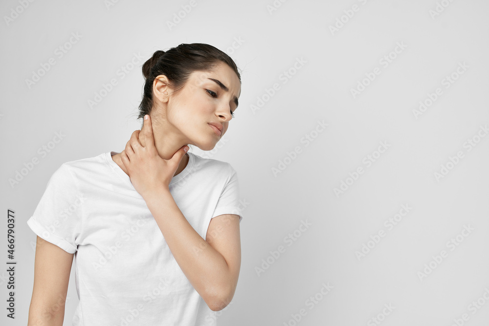 woman in a white t-shirt pain in the neck light background woman in a white t-shirt pain in the neck light background