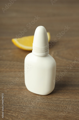 Blank bottle of nasal spray and lemon slice on wooden background