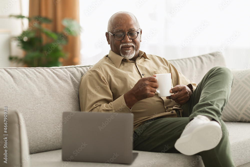 Mature Black Male Watching Movie On Laptop Drinking Coffee Indoor Mature Black Male Watching Movie On Laptop Drinking Coffee Indoor