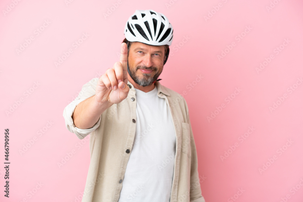 Senior dutch man with bike helmet isolated on pink background showing and lifting a finger Senior dutch man with bike helmet isolated on pink background showing and lifting a finger