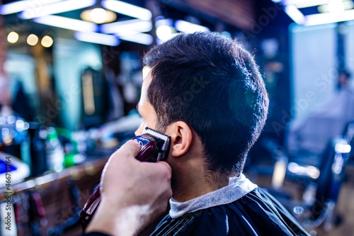 Hairstylist cutting hair of male customer at barber shop