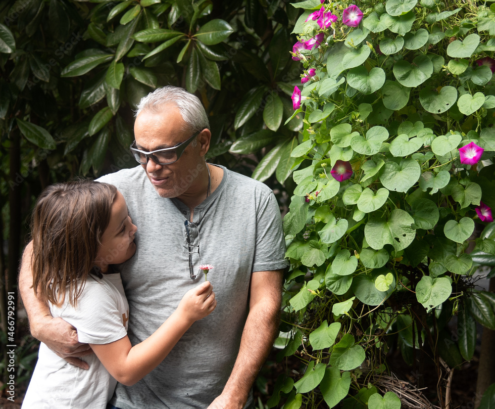 Father or Grandfather with Gray Hair Hugging Young Girl in Garden