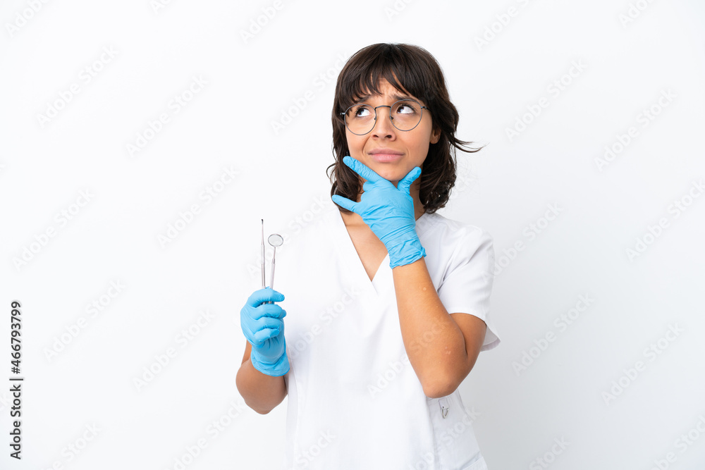 Young woman holding tools isolated on white background having doubts Young woman holding tools isolated on white background having doubts