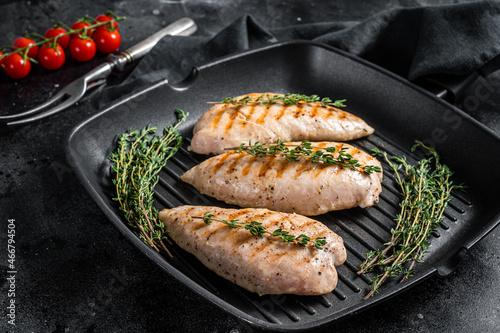 Turkey grilled breast fillet steaks in a frying pan. Black background. Top view