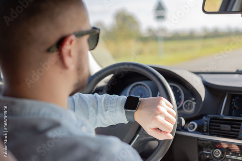 business man in car on road looking on smartwatch.