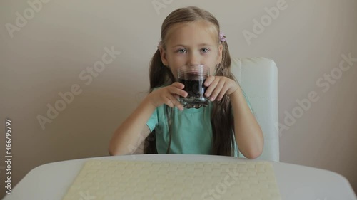 Happy little girl drinking soda from glass