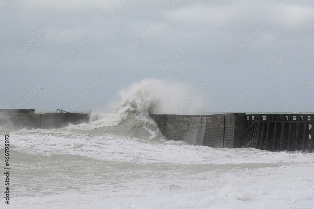 a large wave crashes with a lot of spray over the pier in dieppe at the french coast during a storm in september a large wave crashes with a lot of spray over the pier in dieppe at the french coast during a storm in september